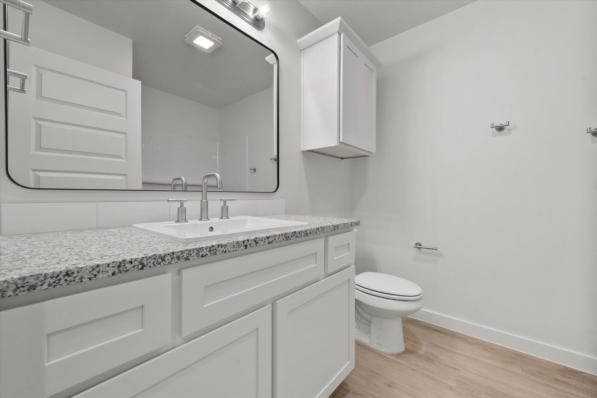 3003 138th Place Lubbock, TX 79423 - Photo 19 of 21 a bathroom with a granite countertop sink a toilet and a mirror