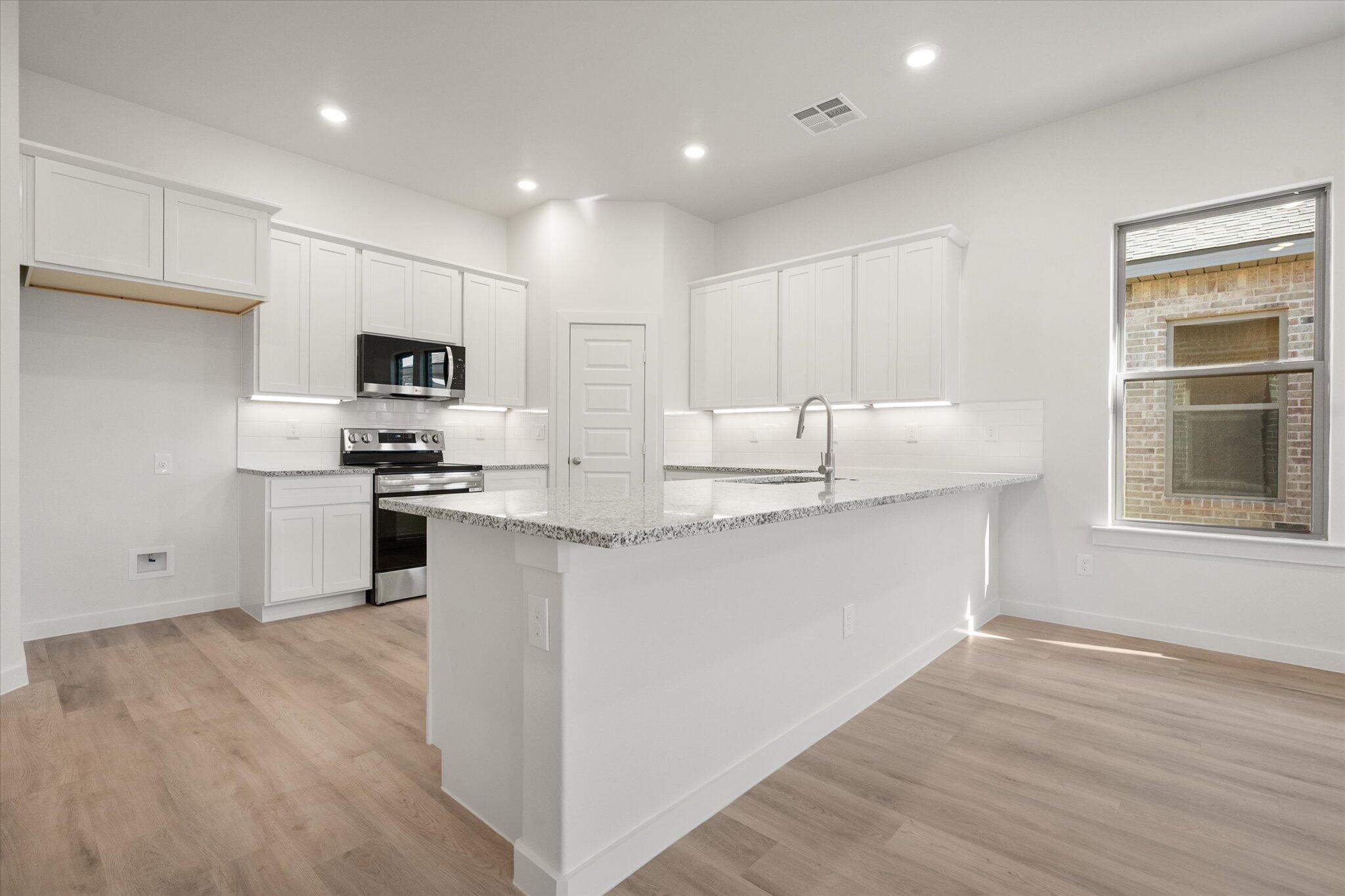 3003 138th Place Lubbock, TX 79423 - Photo 5 of 21 a kitchen with kitchen island granite countertop a sink cabinets and stainless steel appliances