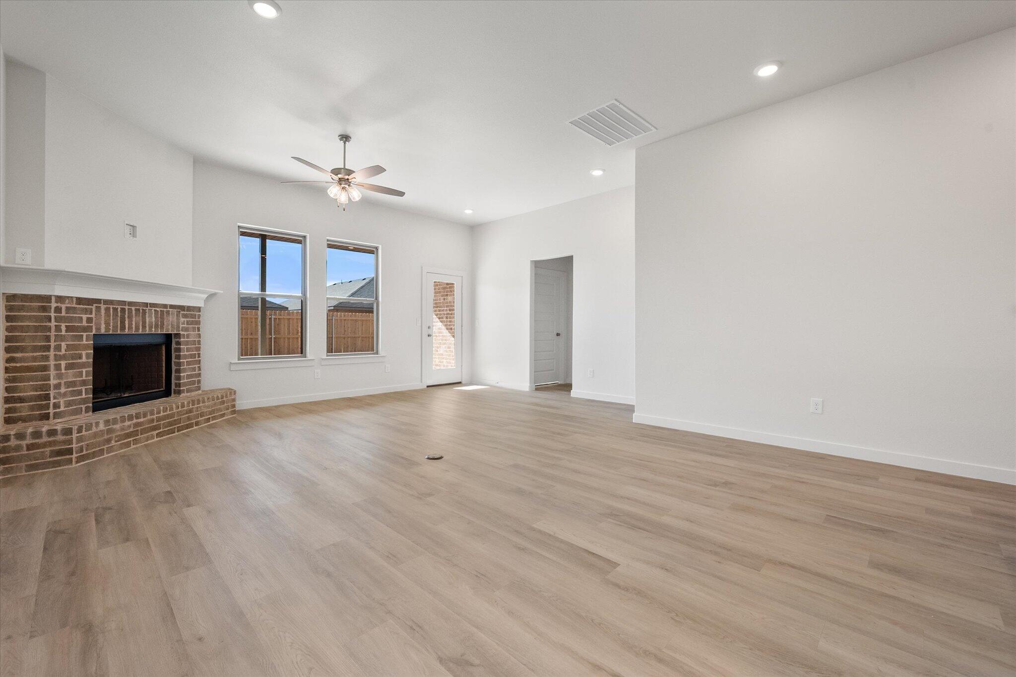 3003 138th Place Lubbock, TX 79423 - Photo 8 of 21 an empty room with wooden floor fireplace and window