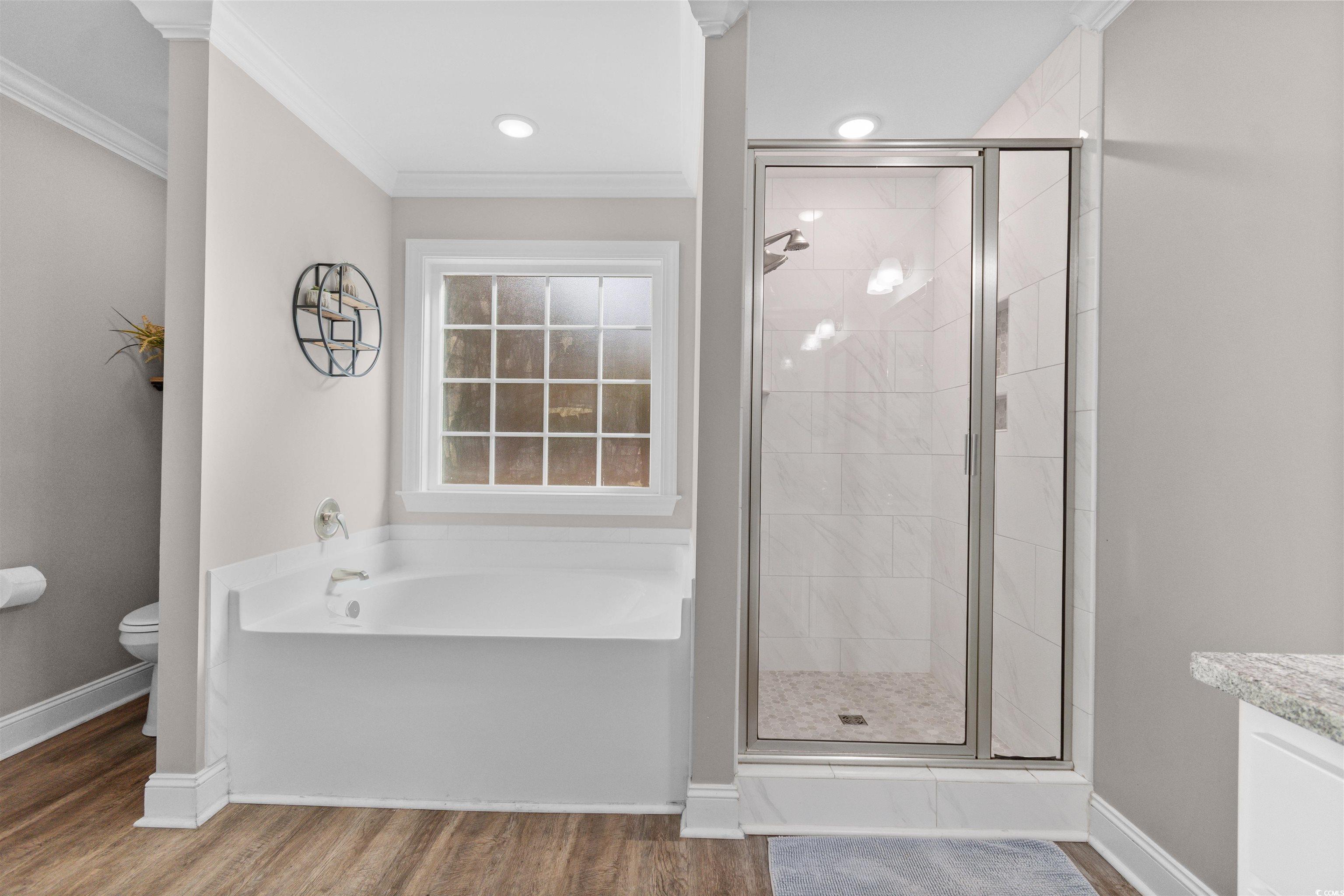 1275 Pinetucky Drive Galivants Ferry, SC 29544 - Photo 16 of 39 Bathroom with a stall shower, wood finished floors, crown molding, a garden tub, and vanity