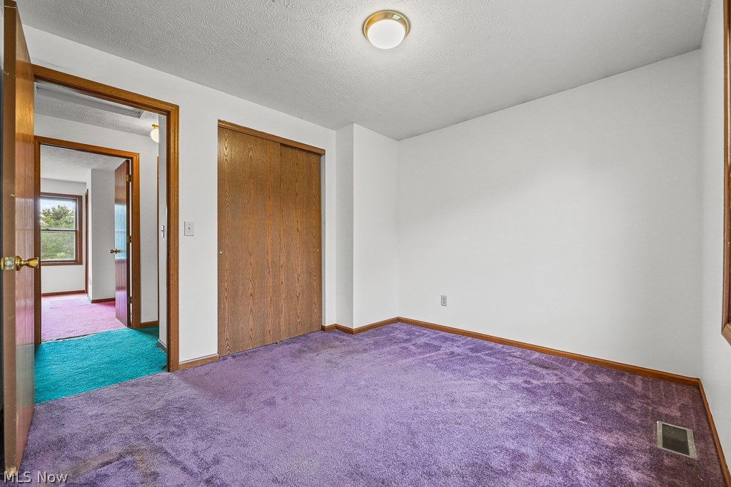 2642 Blake Road Wadsworth, OH 44281 - Photo 30 of 46 Room featuring purple carpeting, white walls, and a built-in closet with wood-finish sliding doors