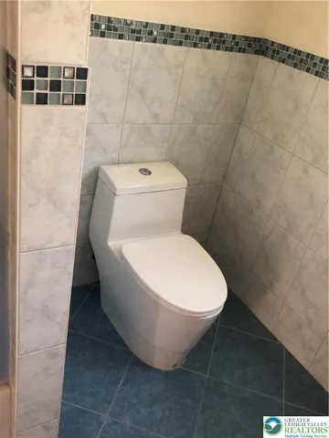 a white toilet sitting next to a white wall