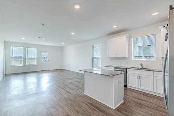 a kitchen with granite countertop a stove a sink and white cabinets with wooden floor