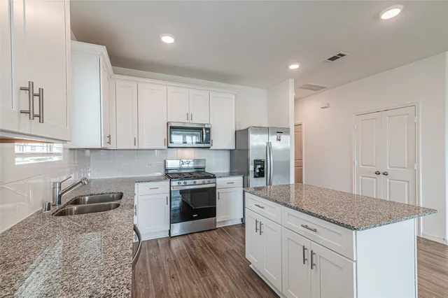 a kitchen with stainless steel appliances granite countertop a sink stove refrigerator and cabinets
