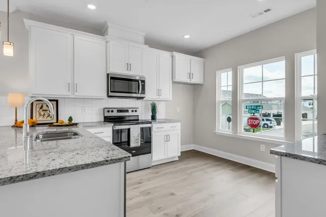 a kitchen with granite countertop a stove a sink and a microwave
