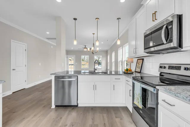 a kitchen with stainless steel appliances granite countertop a stove a sink and a microwave