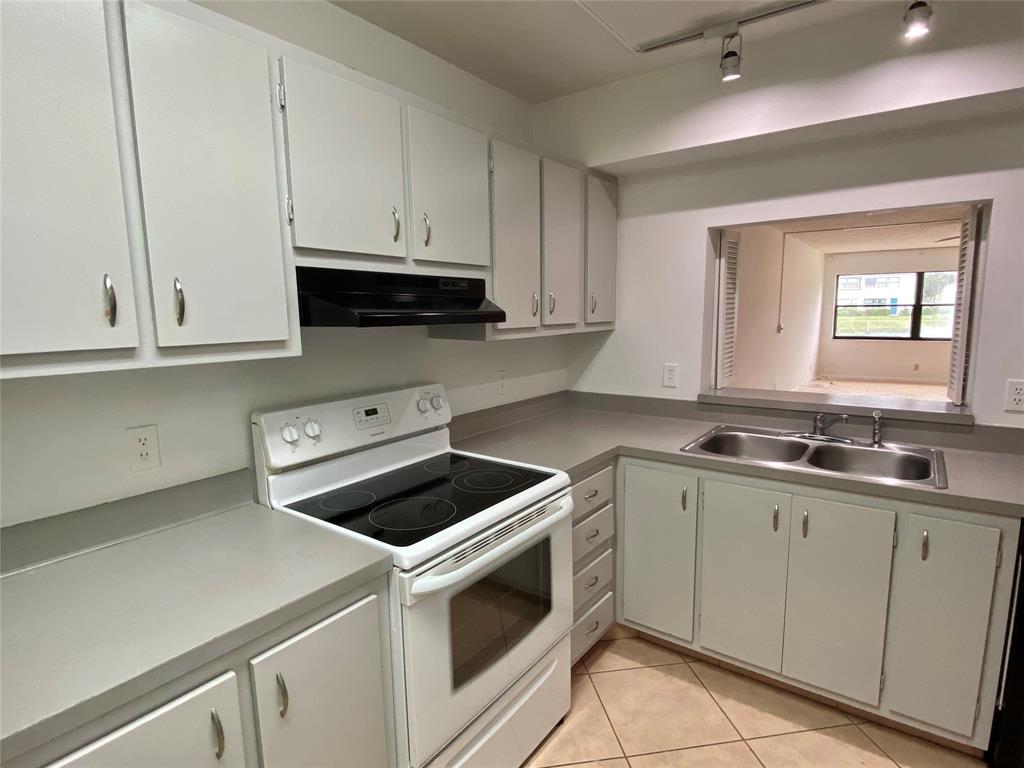 3122 Southwest 20th Terrace, Unit 25B1 Delray Beach, FL 33445 - Photo 5 of 21 a kitchen with white cabinets and white appliances