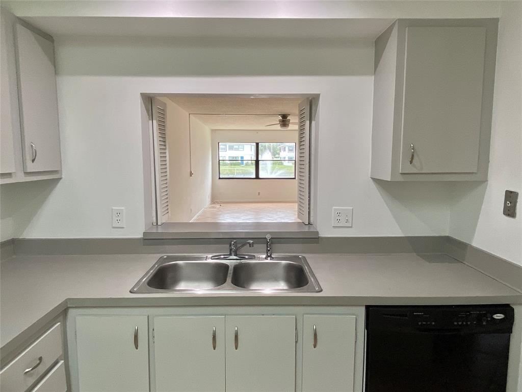 3122 Southwest 20th Terrace, Unit 25B1 Delray Beach, FL 33445 - Photo 6 of 21 a kitchen with a sink cabinets and window