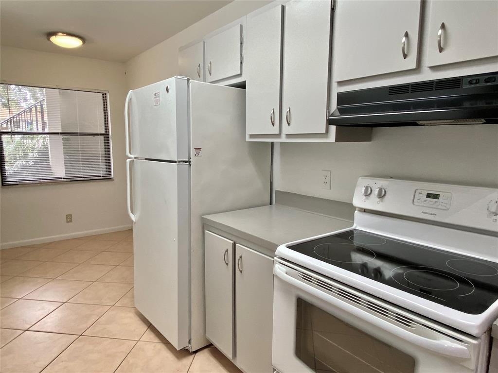 3122 Southwest 20th Terrace, Unit 25B1 Delray Beach, FL 33445 - Photo 7 of 21 a kitchen with a refrigerator and cabinets