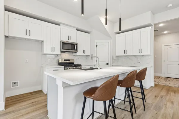 a kitchen with stainless steel appliances a stove a sink a refrigerator and a microwave