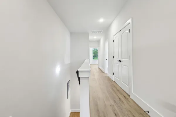 a view of a hallway with wooden floor and staircase
