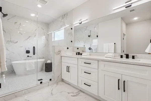 a spacious bathroom with a double vanity sink mirror and bathtub
