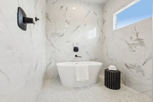 a bathroom with a granite countertop sink a mirror a bathtub and shower
