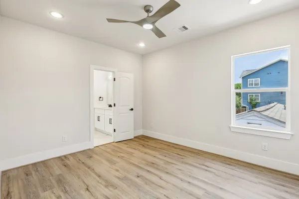 an empty room with wooden floor and a ceiling fan
