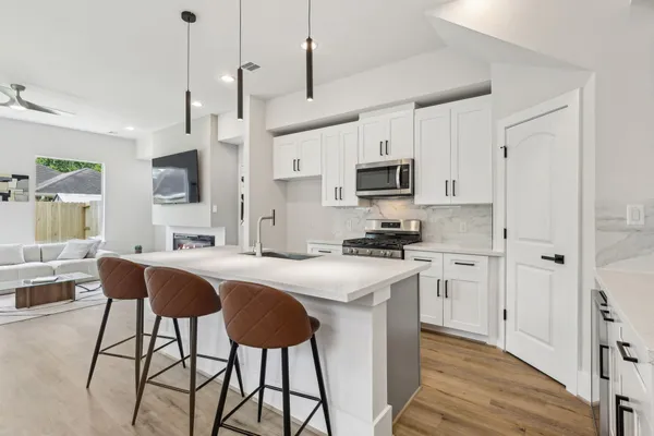 a kitchen with stainless steel appliances granite countertop a sink a stove a refrigerator cabinets and chairs