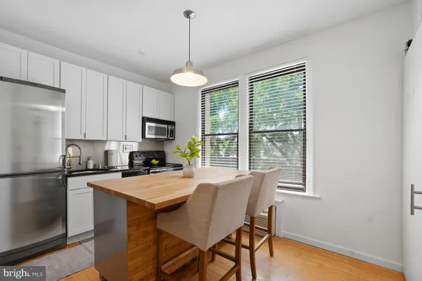 a kitchen with a refrigerator a stove cabinets and a dining table