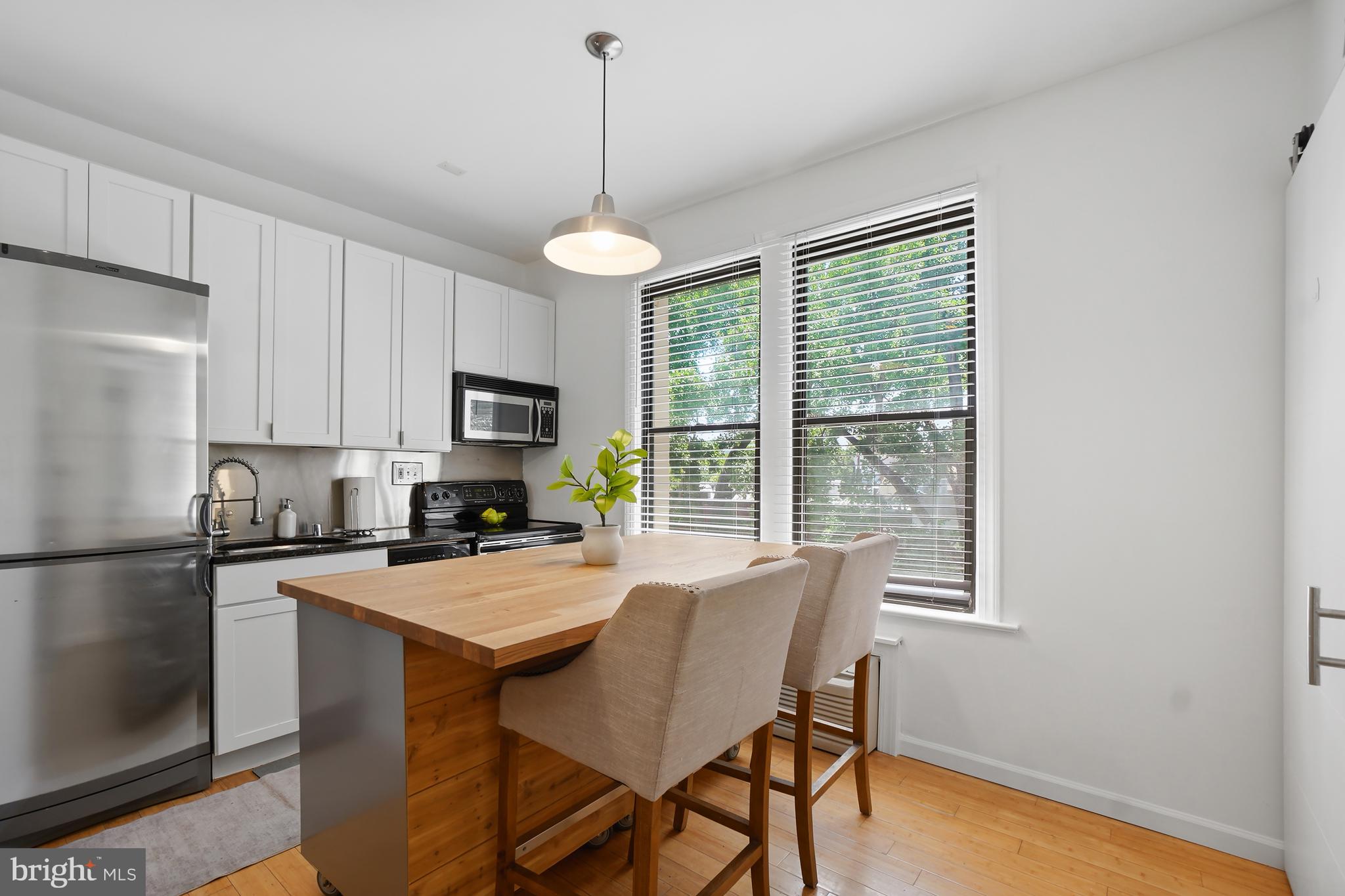 1822 15th Street Northwest, Unit 303 Washington, DC 20009 - Photo 1 of 22 a kitchen with a refrigerator a stove cabinets and a dining table