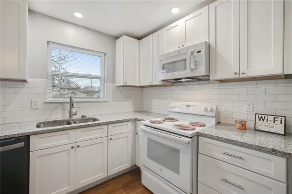 a kitchen with cabinets appliances a sink and a window