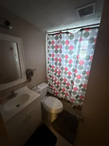 a bathroom with a sink toilet and shower curtain