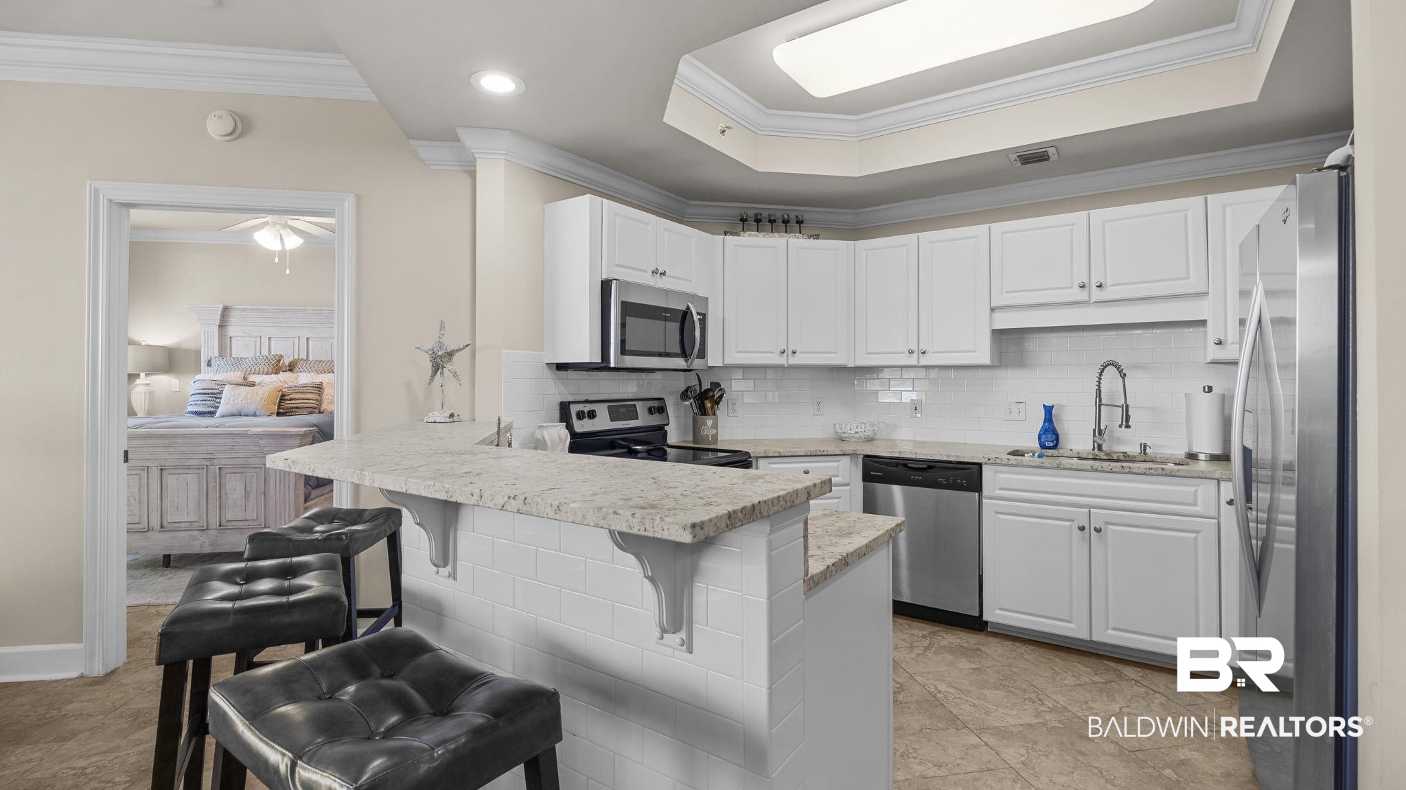 27580 Canal Road, Unit 1526 Orange Beach, AL 36561 - Photo 9 of 49 Kitchen with crown molding, decorative backsplash, appliances with stainless steel finishes, white cabinets, and a kitchen breakfast bar