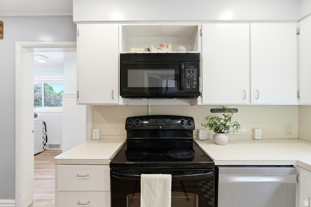 210 North 200 West Logan, UT 84321 - Photo 10 of 31 Kitchen featuring white upper and lower cabinetry, a black electric range, and a built-in black microwave