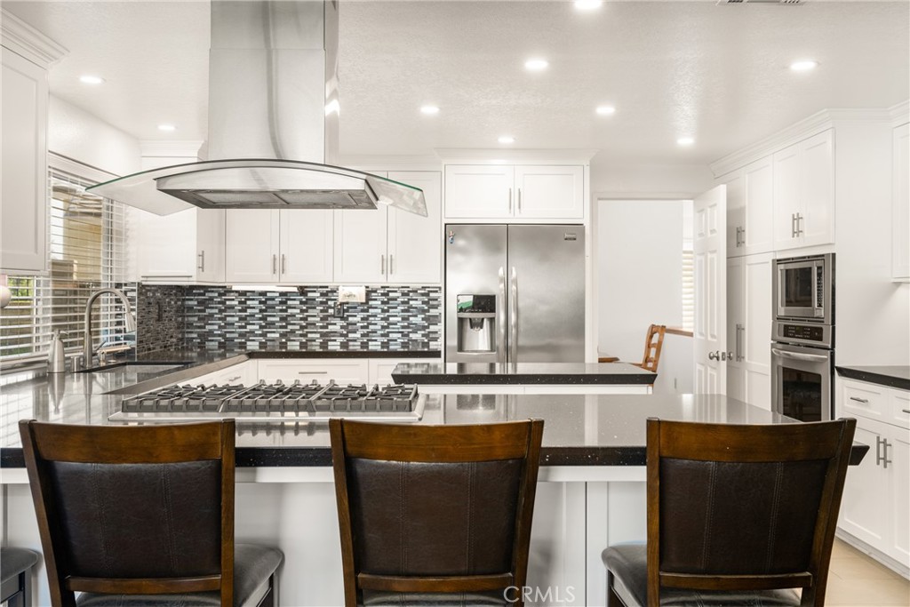 3250 North Geronimo Avenue Simi Valley, CA 93063 - Photo 20 of 47 a kitchen with stainless steel appliances granite countertop a stove a refrigerator a sink a dining table and chairs