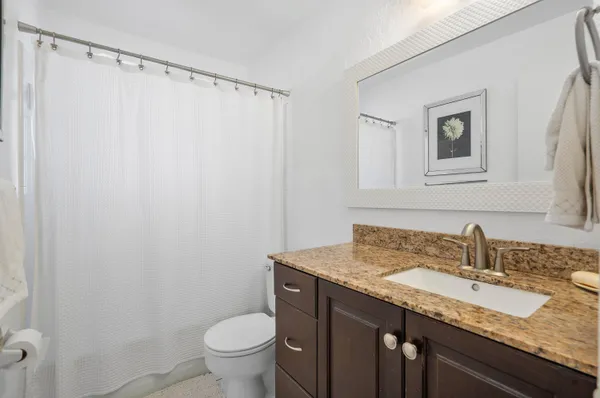 a bathroom with a granite countertop sink toilet and a mirror