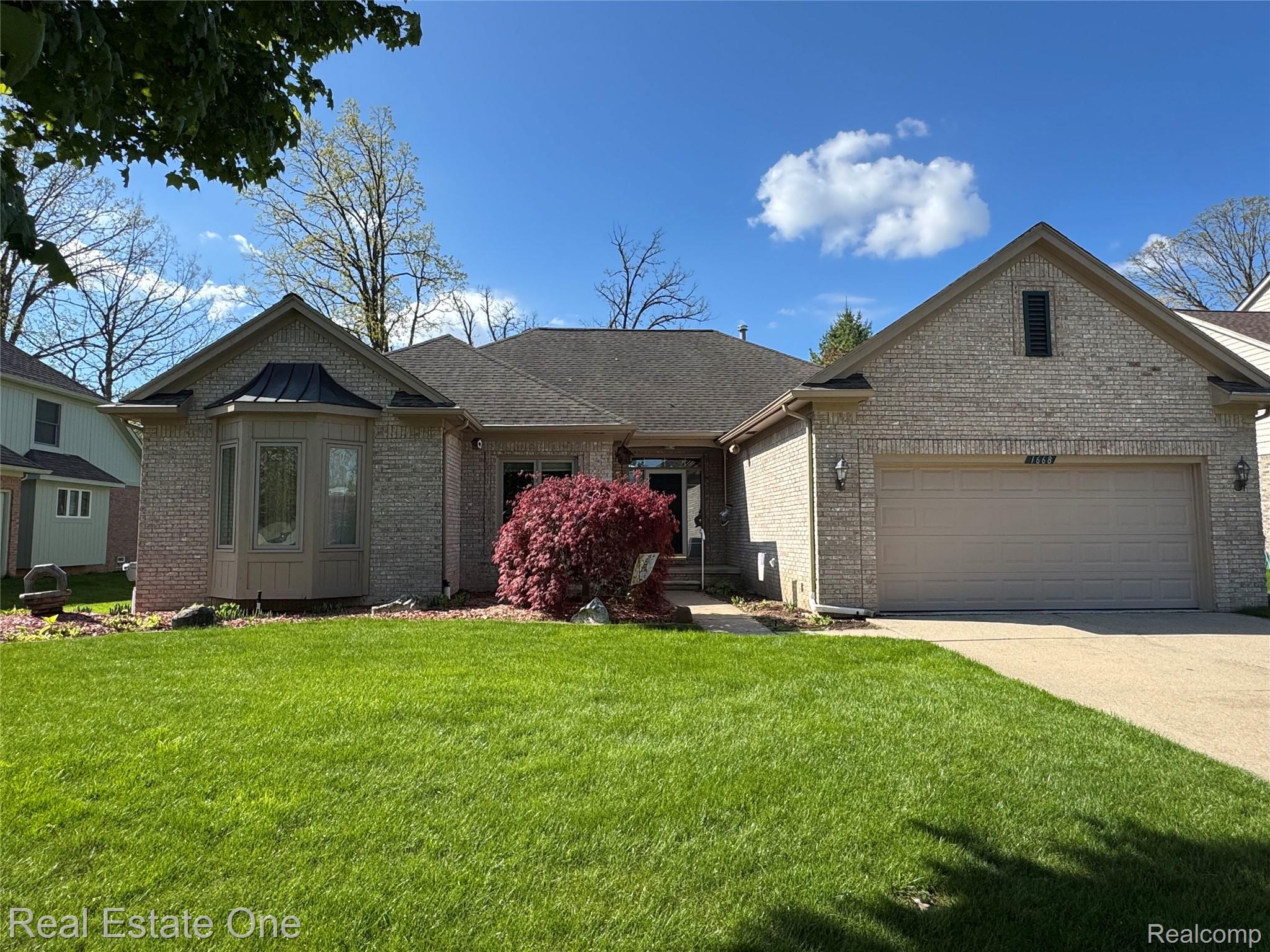 1668 South Shore Drive Rochester, MI 48307 - Photo 1 of 27 View of front of property with a garage, brick siding, a front lawn, and concrete driveway