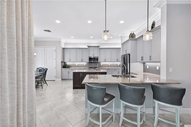 a kitchen with kitchen island granite countertop stainless steel appliances a sink dishwasher a refrigerator and white cabinets