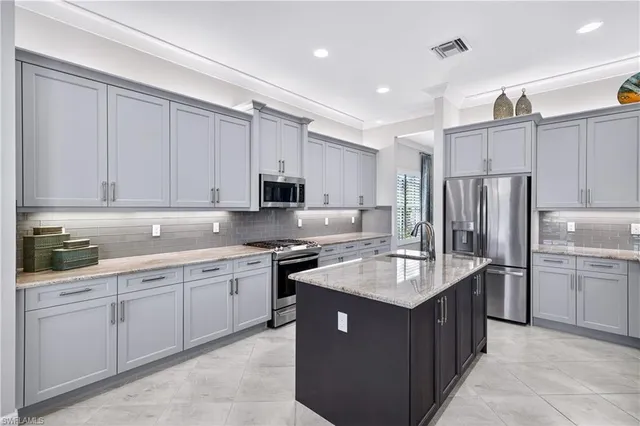 a kitchen with kitchen island a counter top space a sink stainless steel appliances and cabinets