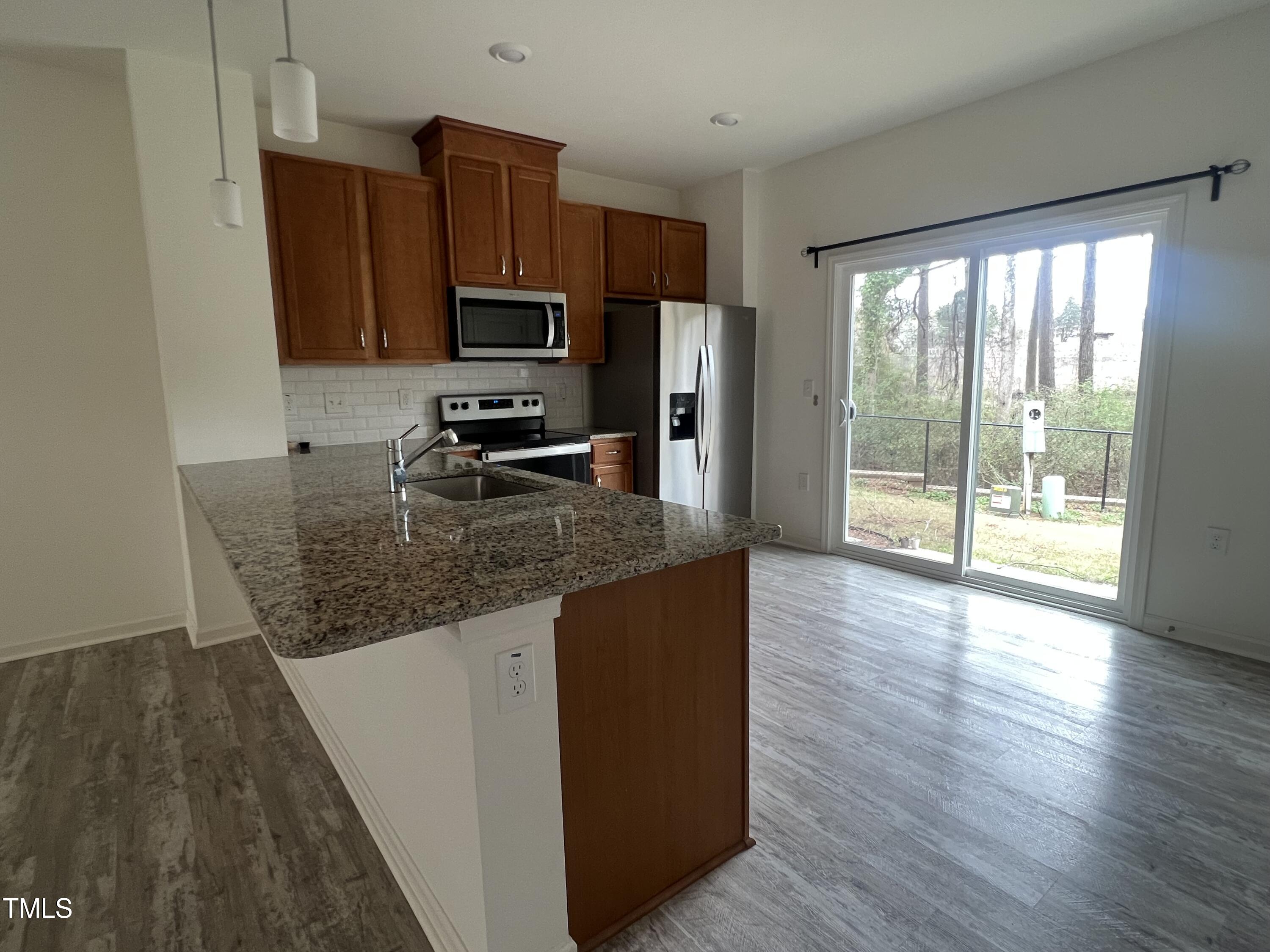 3118 Crater Loop Raleigh, NC 27610 - Photo 5 of 14 a kitchen with granite countertop a refrigerator a stove top oven a sink and wooden floors