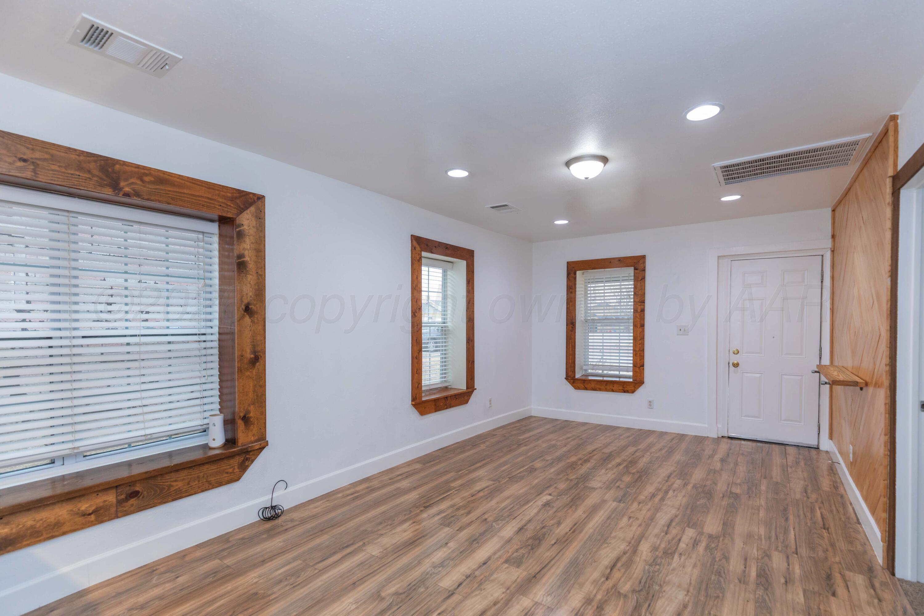 1503 7th Avenue Canyon, TX 79015 - Photo 2 of 30 a view of an empty room with wooden floor and a window