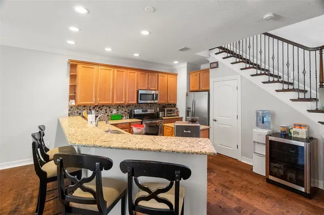 a kitchen with granite countertop a stove a sink a dining table and chairs