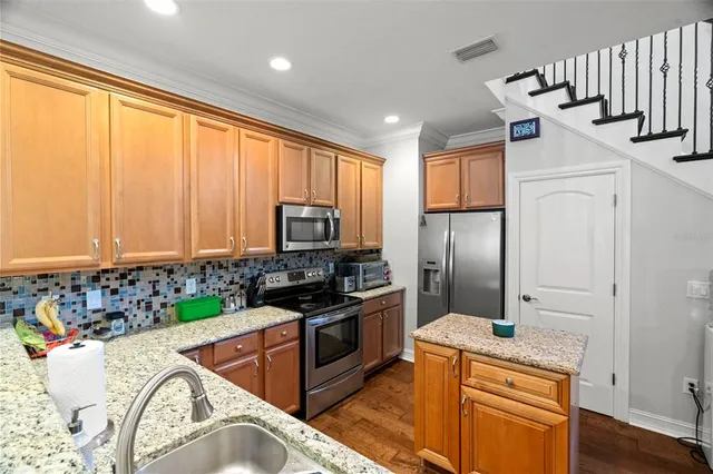 a kitchen with stainless steel appliances granite countertop a sink a stove and a refrigerator