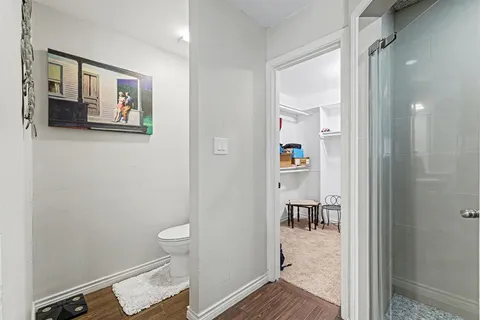 a view of a hallway with wooden floor and a bathroom