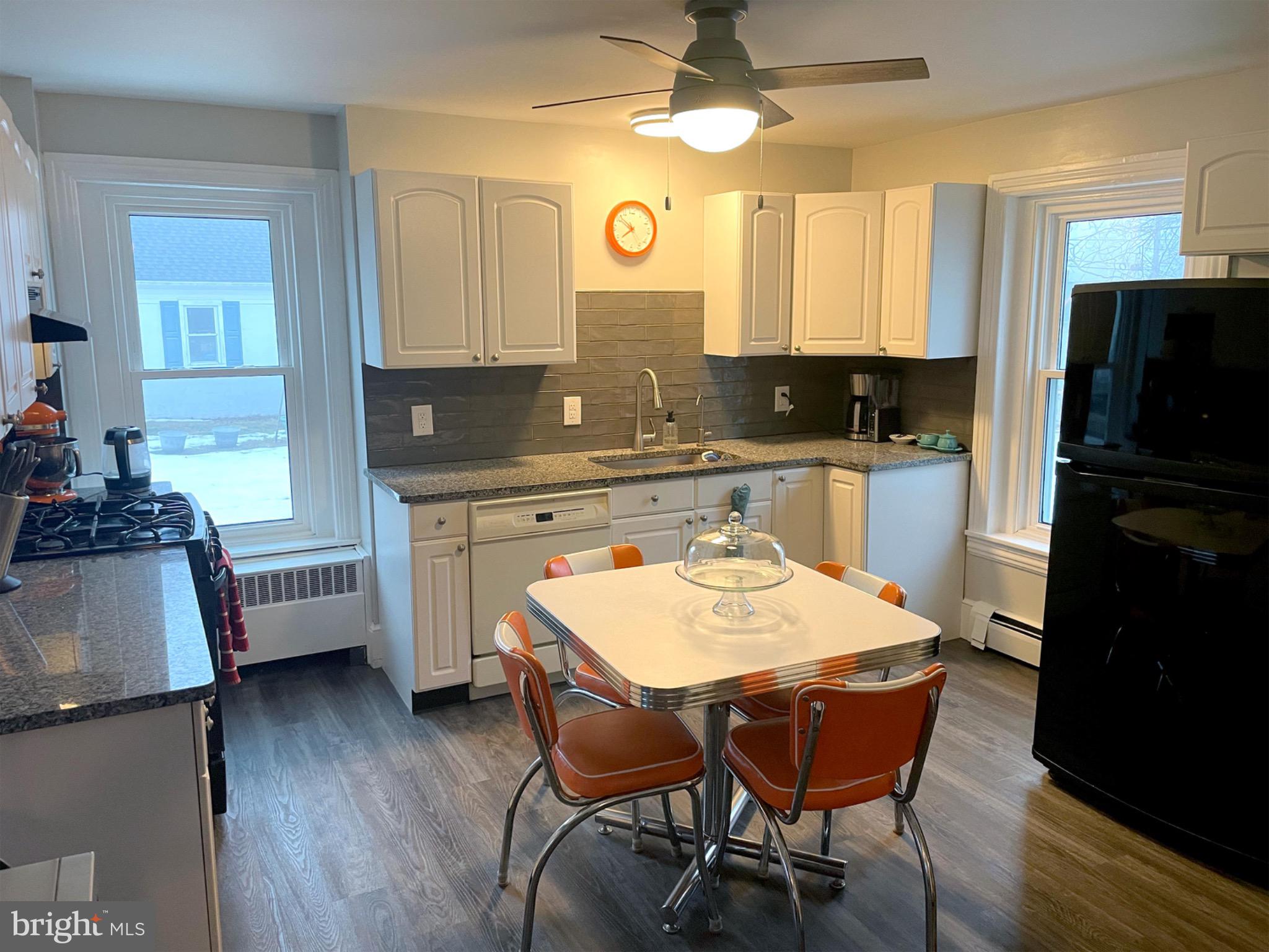245 Maple Street Oxford, PA 19363 - Photo 7 of 23 a kitchen with a refrigerator a stove a sink dishwasher and a dining table with wooden floor