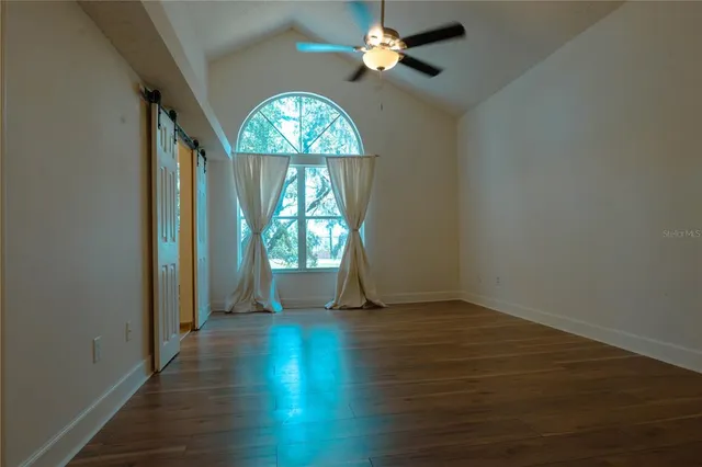 an empty room with wooden floor fan and windows