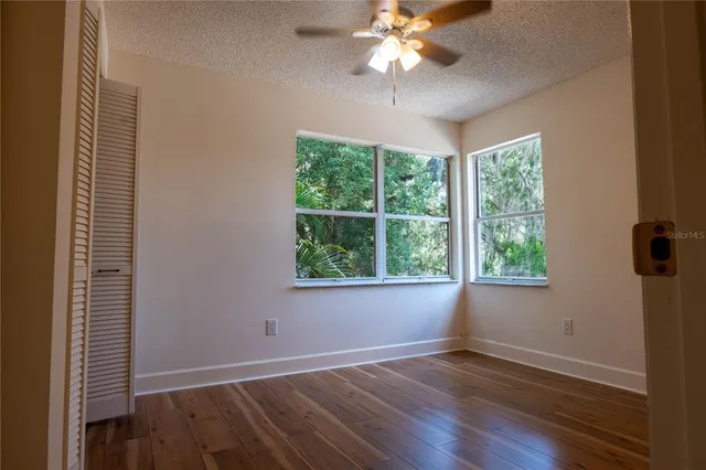 an empty room with wooden floor and windows