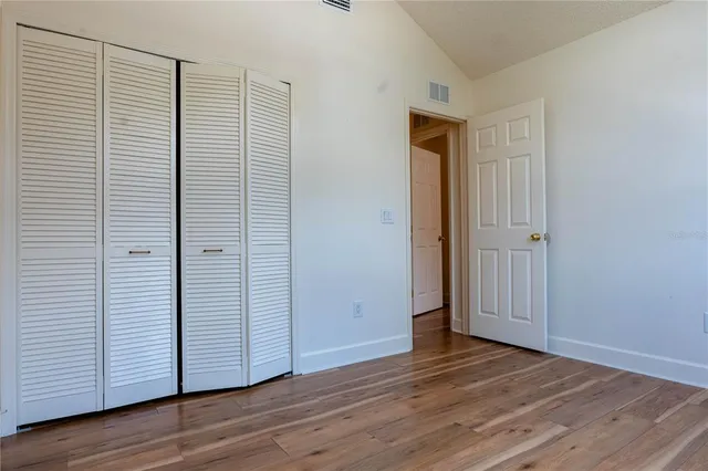 an empty room with wooden floor and closet area