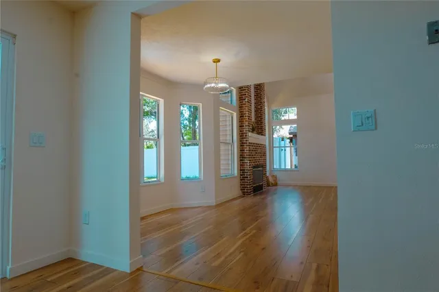 a view of an empty room with window and wooden floor