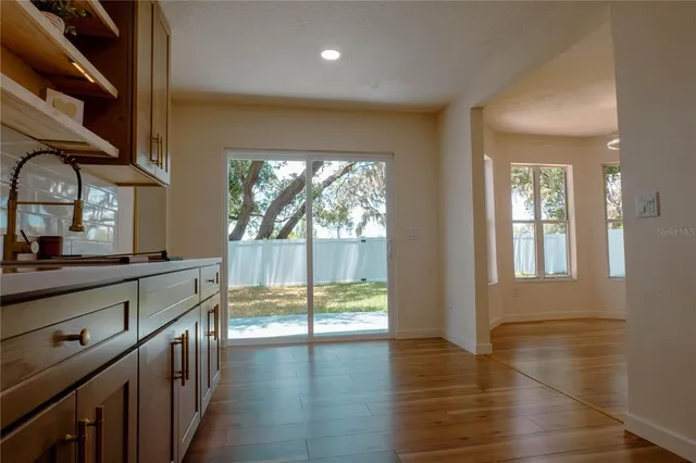a kitchen with stainless steel appliances wooden floor and a large window