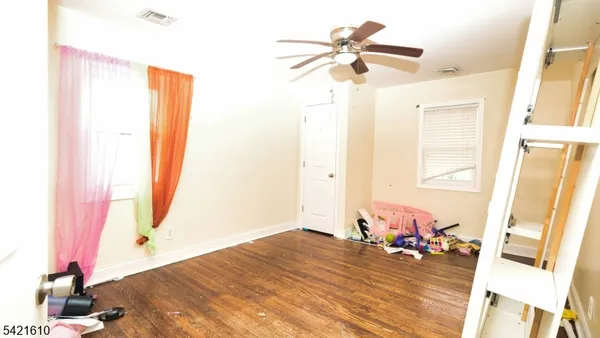 a view of a bedroom with wooden floor and ceiling fan