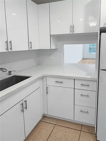 a kitchen with white cabinets and sink