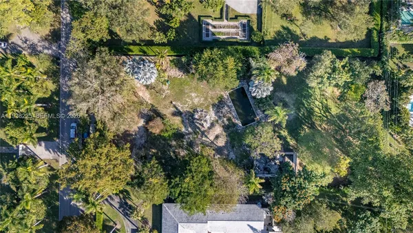 an aerial view of residential house with outdoor space and trees all around