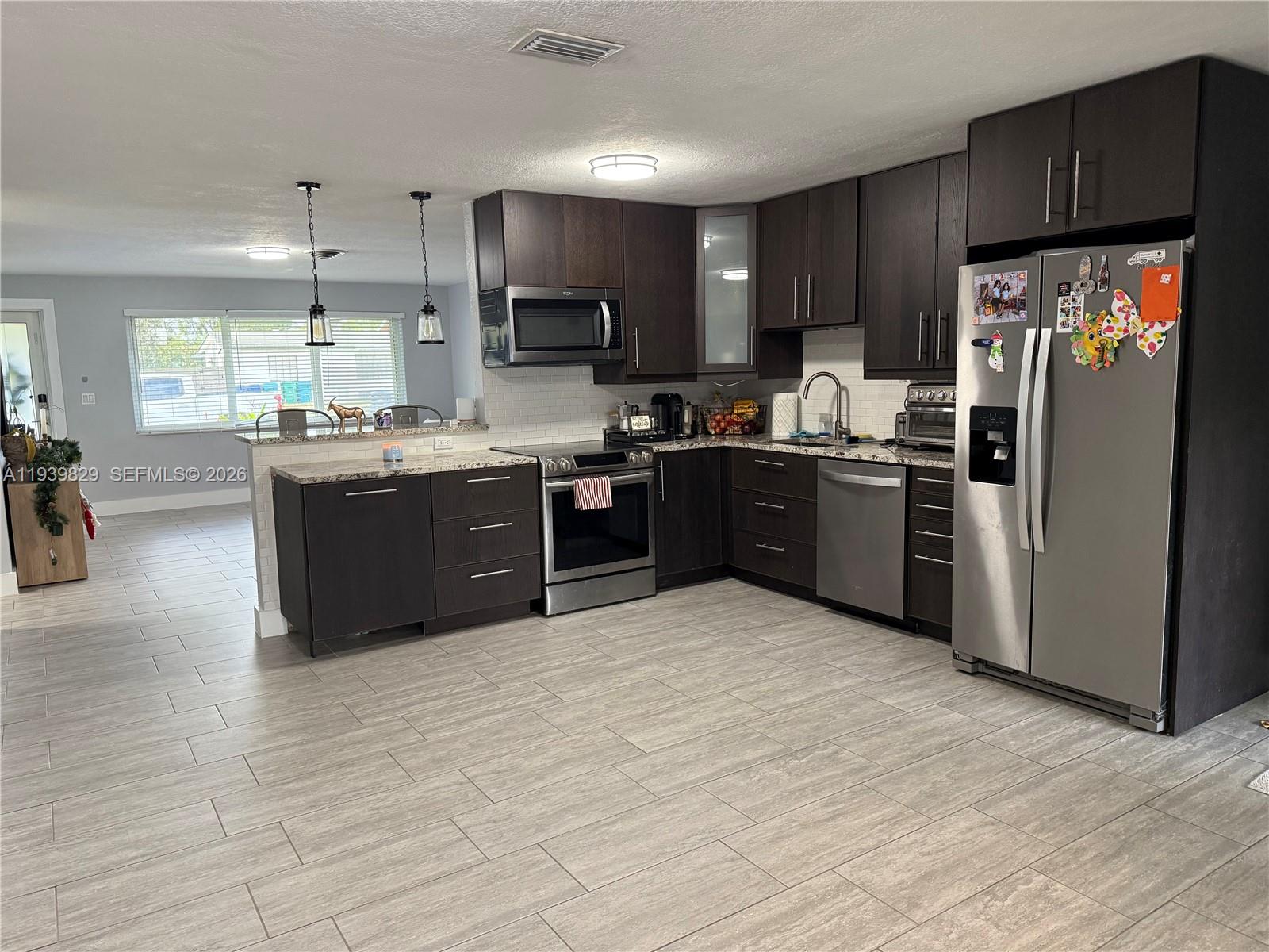 5280 Southwest 92nd Terrace Cooper City, FL 33328 - Photo 31 of 50 a kitchen with stainless steel appliances granite countertop a stove top oven a refrigerator a sink and dishwasher