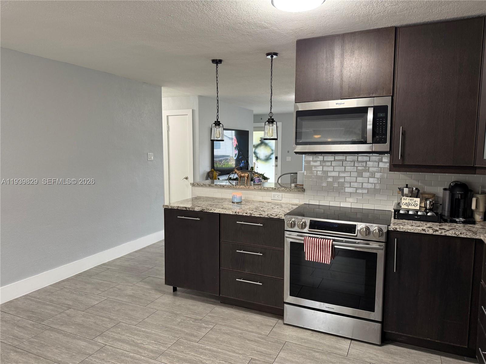 5280 Southwest 92nd Terrace Cooper City, FL 33328 - Photo 32 of 50 a kitchen with stainless steel appliances granite countertop a stove a sink and a microwave