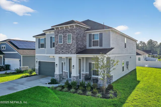 a view of a house with brick walls and a yard with plants