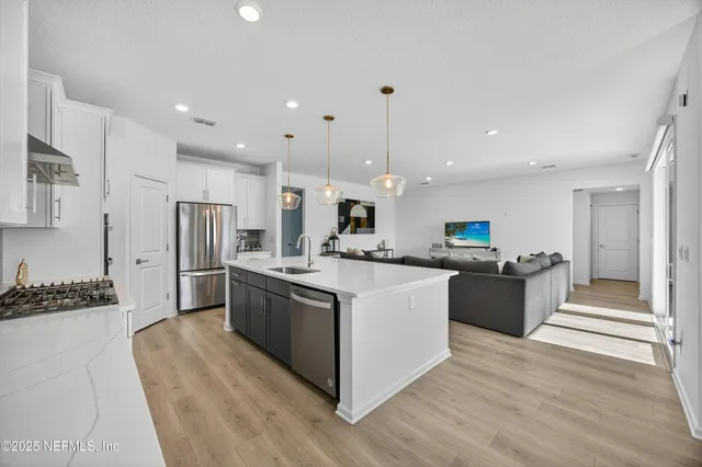 a kitchen with stainless steel appliances kitchen island granite countertop a sink a stove and cabinets