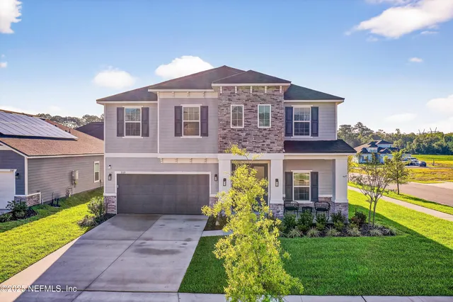 a view of a house with a big yard and large tree