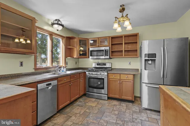 a kitchen with stainless steel appliances granite countertop a stove refrigerator and a sink